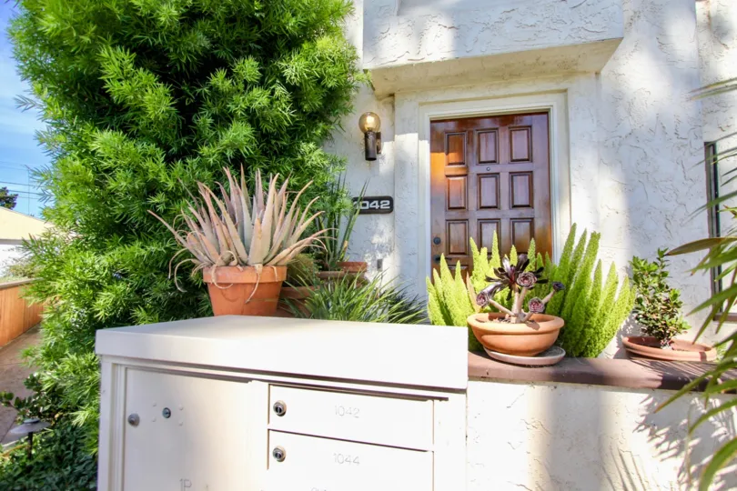 A frontyard of a residence in the Opal Townhomes community with an exterior locker and a large shrub.