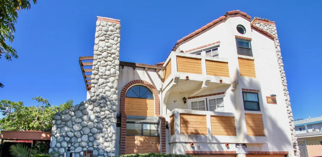 Rock chimney and wood siding on white stucco at Pacific Gardens II in Pacific Beach, California