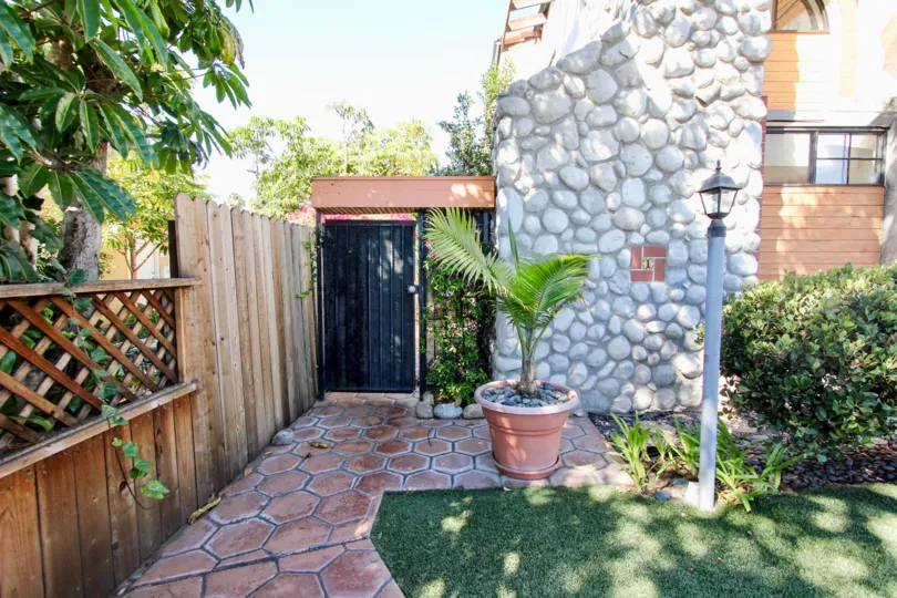 Large outdoor space with a lovely garden sitting area with palm trees and lighting.