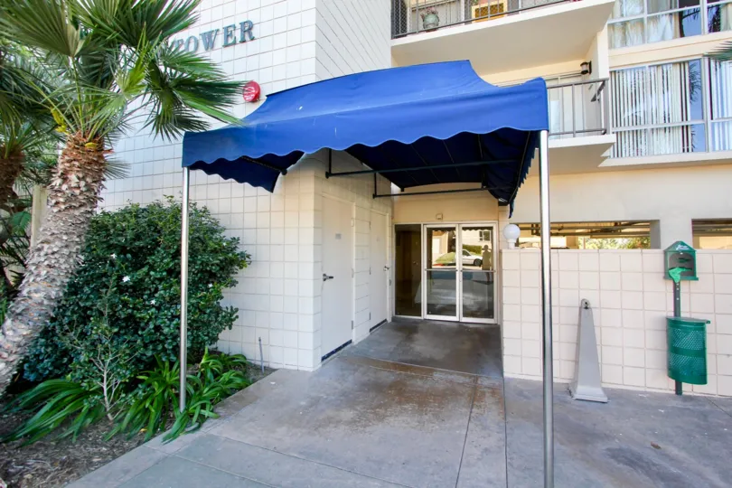 A sunny day in the area of Pacific Tower, outside, garbage can, door, awning, palm tree, balcony