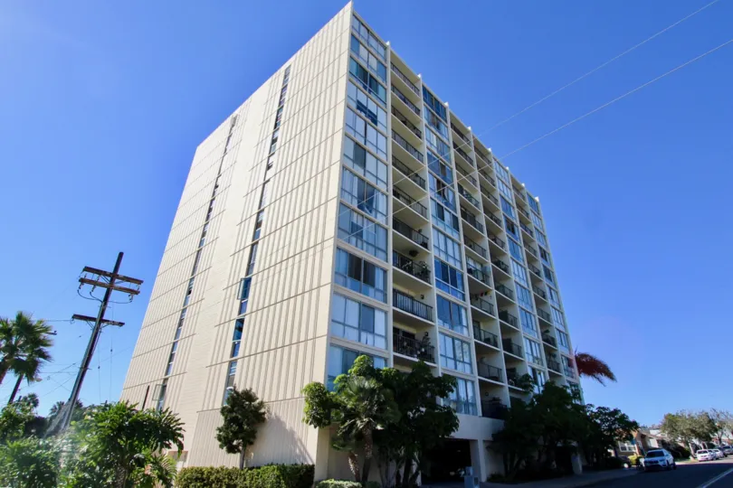 Apartments with grey colored walls and many trees surrounding the area.