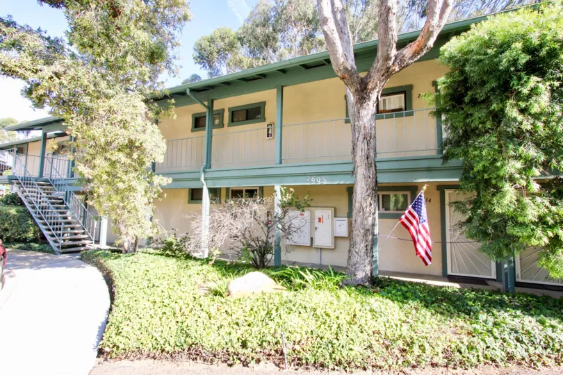 A sunny day in the area of Pacific Woodlands, outside, balconies, condos, tree, car, flag