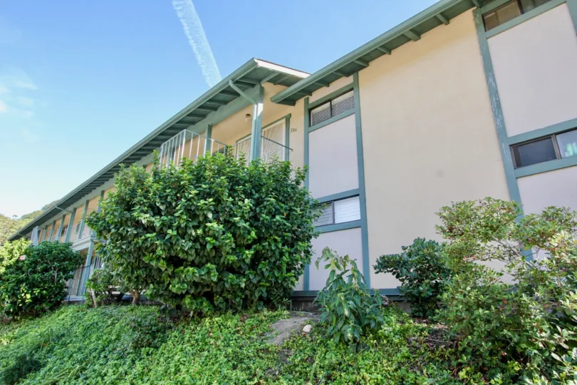 A townhouse with cream walls and green trimmings in the Pacific Woodlands community.