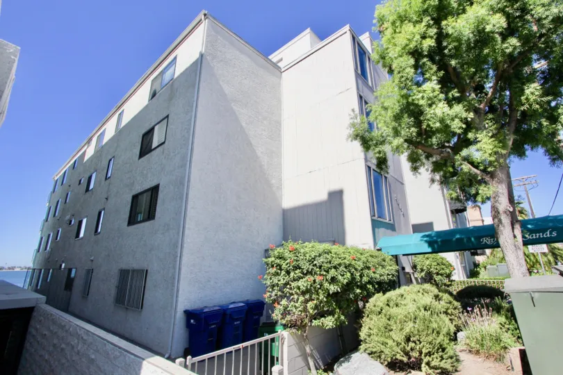 Multistorey apartments in the Riviera Sands neighborhood with large tree and shrubs.