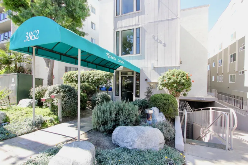 A covered entryway to the Riviera Sands community with white walls and turquoise porch.