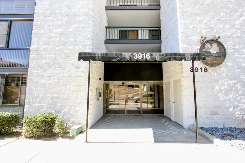 A luxe entryway to the Riviera Shores community with black covered porch and brass doors.