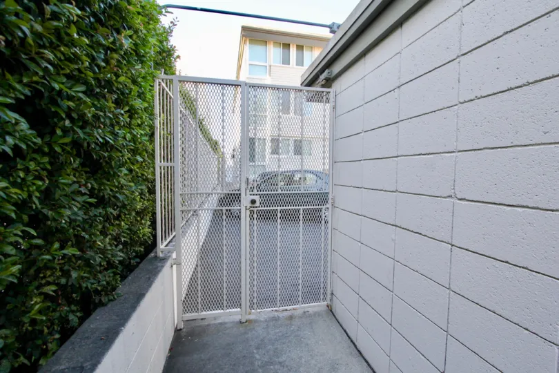 A Good view of house with parking and a grilled gate with trees around of Sail bay Shores in Pacific Beach
