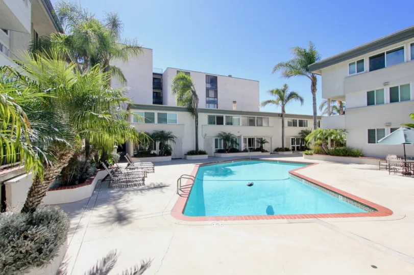 A Bright sunny day with a swimming pool at centre of villas with trees in Sail Bay Shores of Pacific Beach