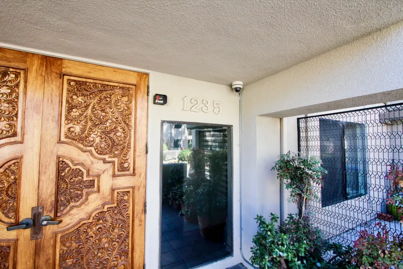 A well artificial wooden door of a building in the Santa Susanna with some plants and iron grill also.