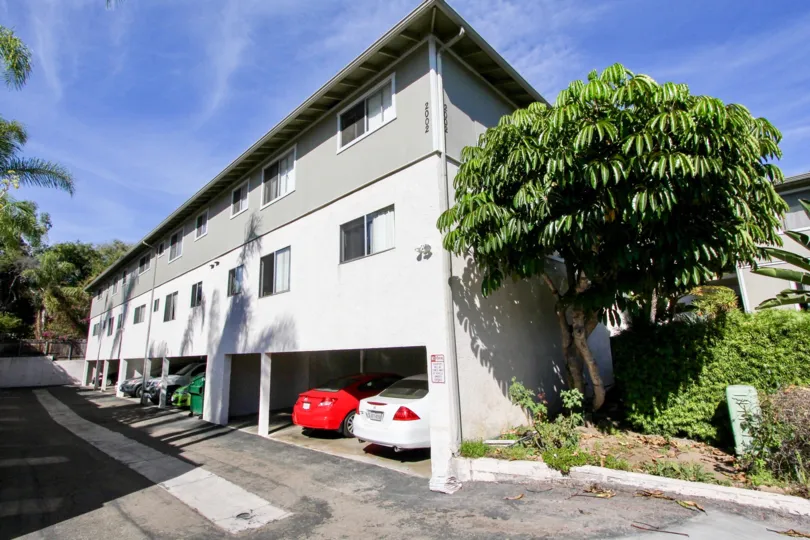 A sunny day in the area of Scott House, condos, car port, vehicles, trees, driveway