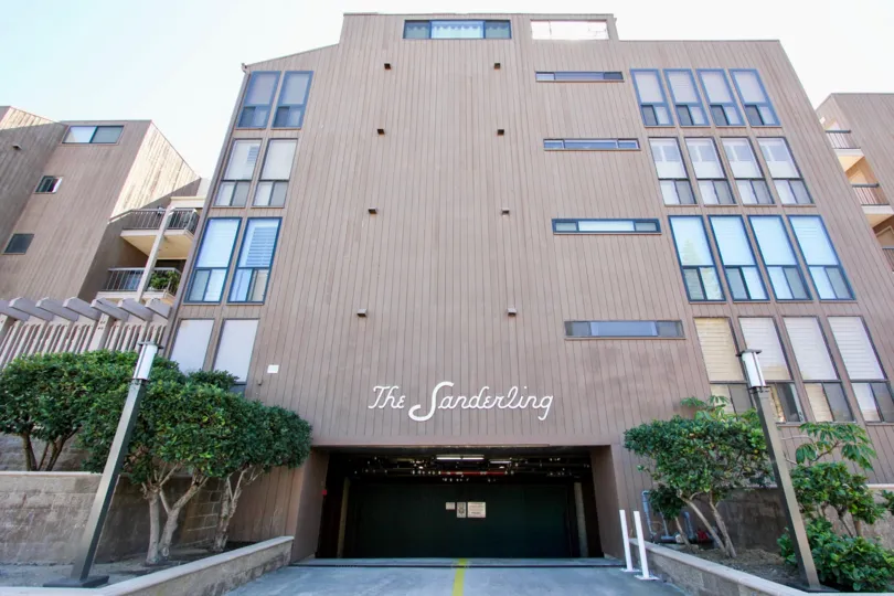 A tall building on a sunny day with garage parking at the Sanderling Community