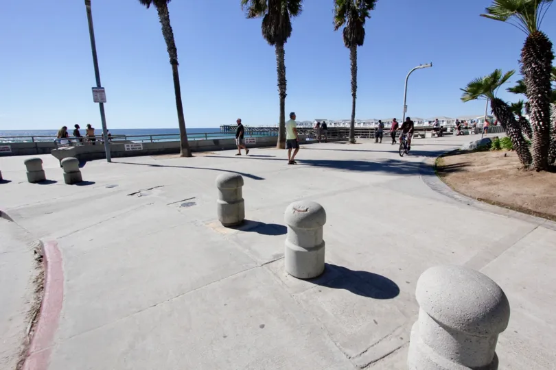 Cement posts on the sidewalk with people at See the Sea, Pacific Beach, California