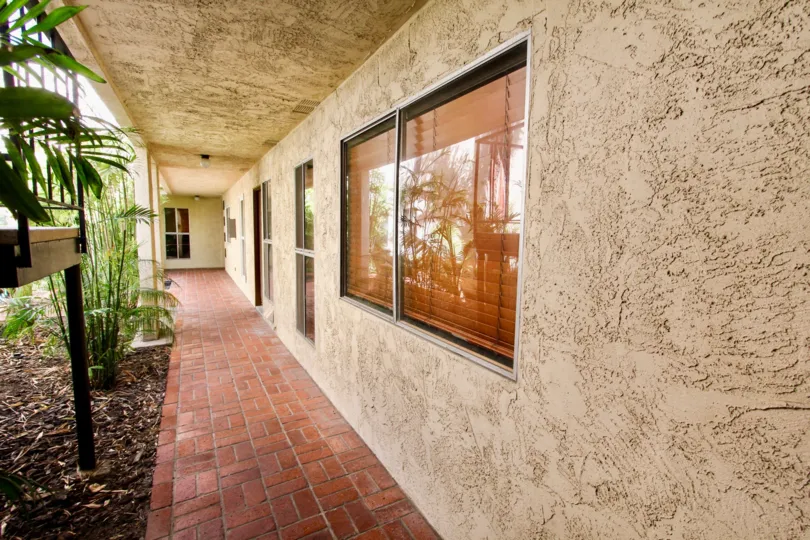 A tiled hallway with stucco walls and sliding windows in the Shasta Daisy community.
