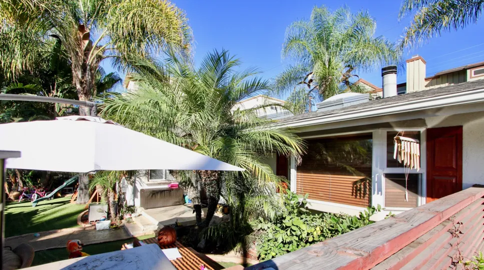 a backyard of a home with a lot of palm tree and a white shade in Sunblend community