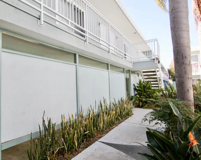 back stair view of the heritage on diamond building all white with palm tree