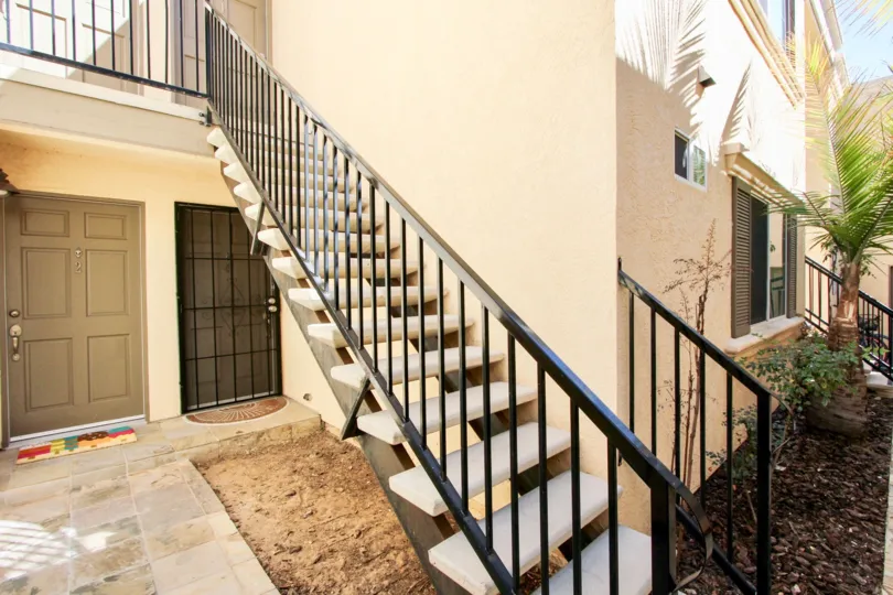 An exterior staircase in theThomas Avenue Condominiums above a bare soil.