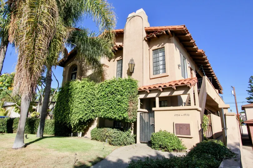A two-storey traditional residence with a tall shrub and pine tree in the Vista Adelle Mar community