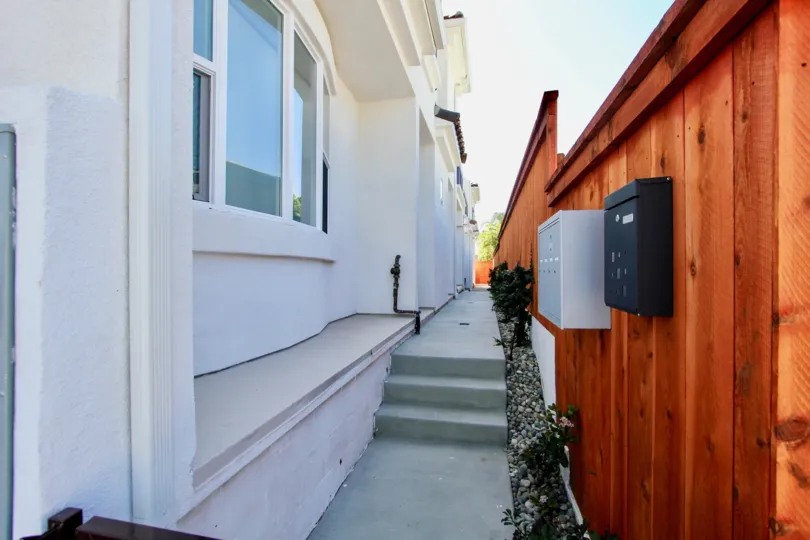 A black box and a row of mailboxes sits on a brown privacy fence at Keats Place