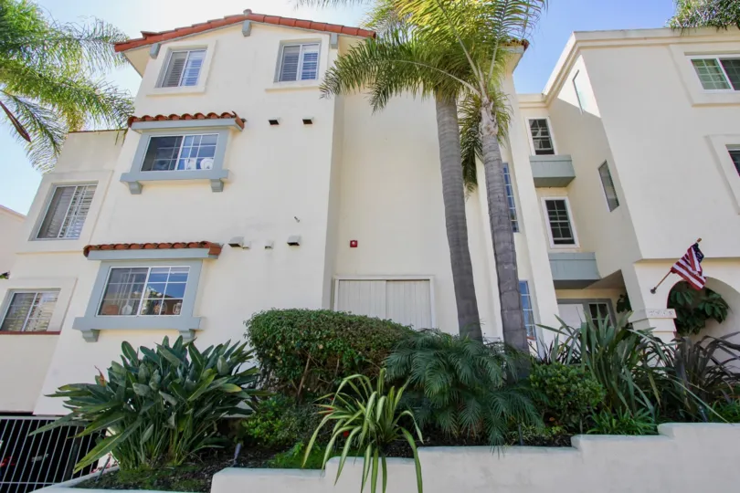 Three story condo with palm trees in front, located in La PLaya Blanca, Point Loma, California.