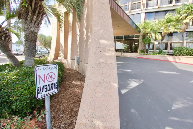 The front entrance to Le Rondelet features several palm trees and a covered driveway.