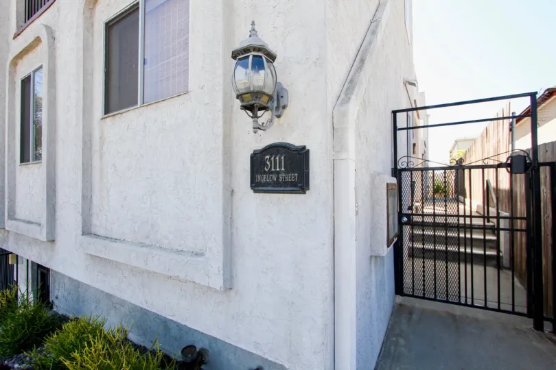 Primrose Gardens, Point Loma, California. A black gate sits adjacent to a white stone building.