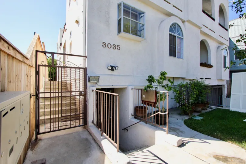 A wooden privacy fence shifts up as the sidewalk ascends with stairs at Primrose Villas