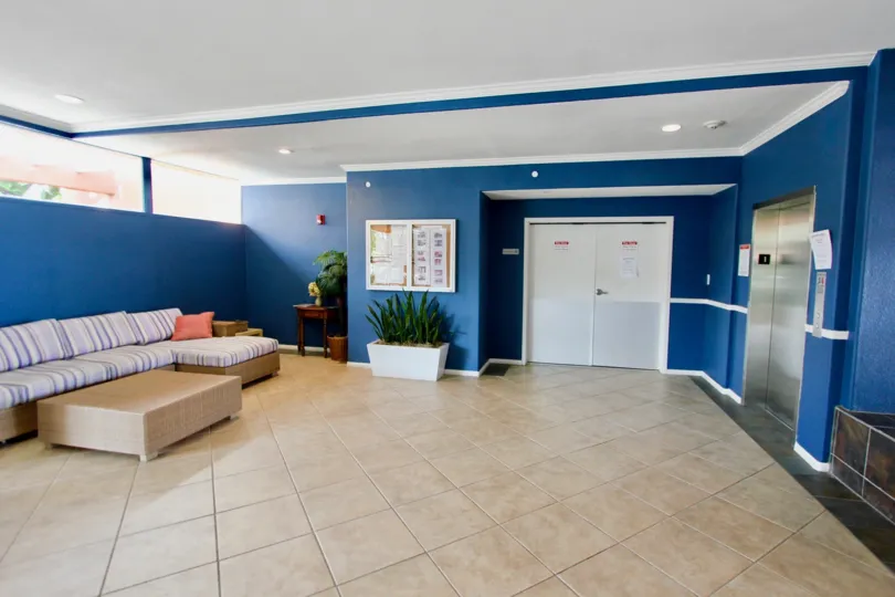 An easy to maintain lobby has tile flooring and dark blue walls.