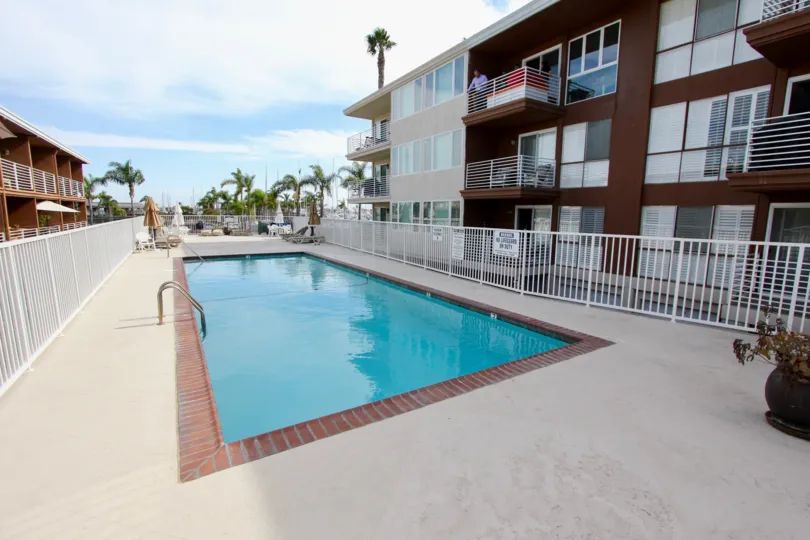 Private fenced-in swimming pool with sizeable pool deck surrounded by palm trees at Yacht Club Condos
