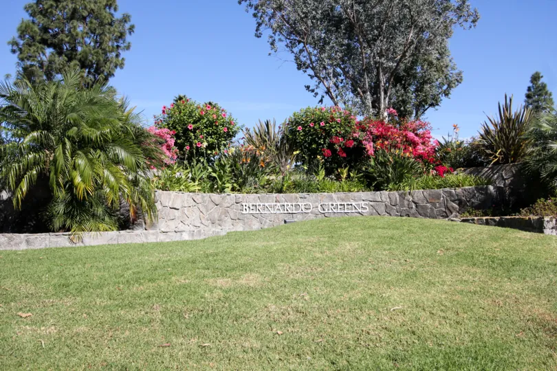 White sign on a broad stone wall near trees at Bernardo Greens in Ranch Bernardo CA