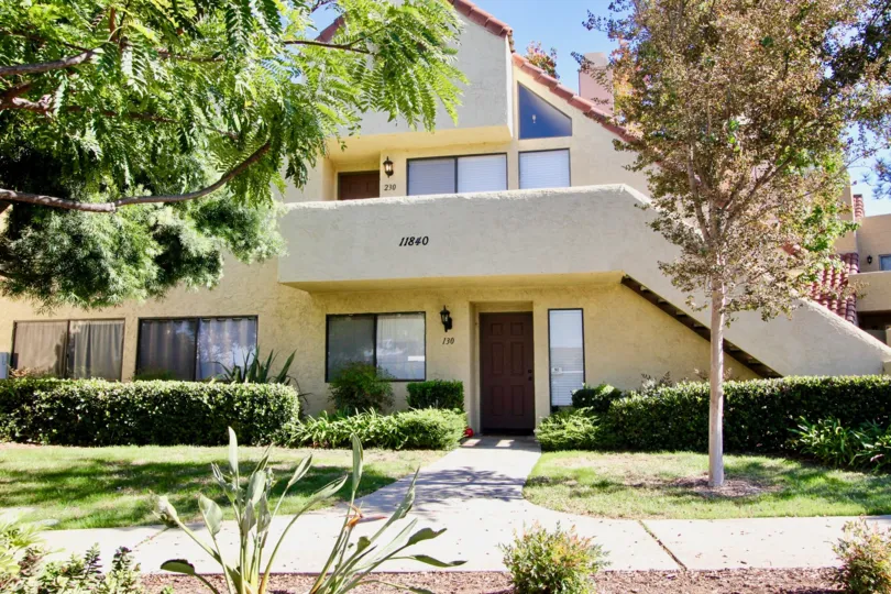 A light yellow house with some trees in front and bushes in Bernardo Pines, Rancho Bernardo, CA