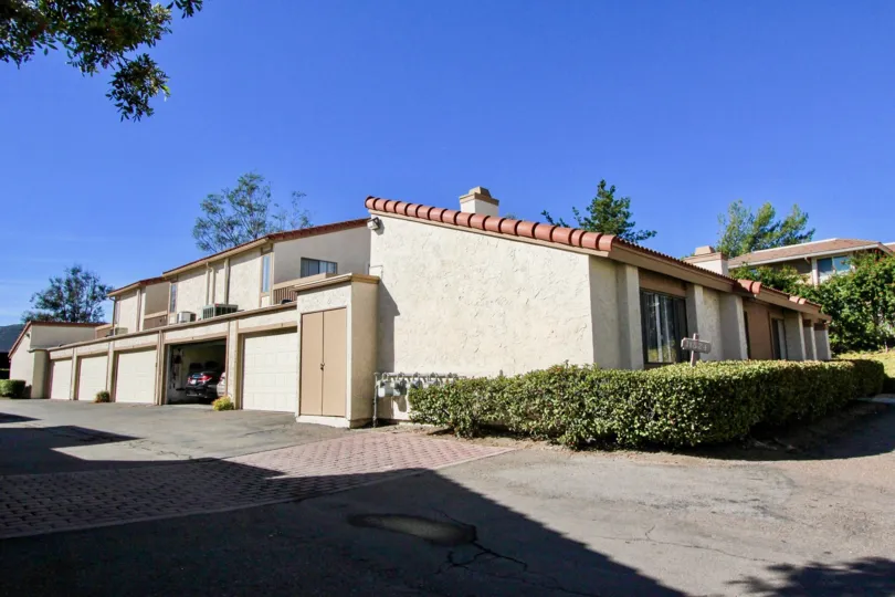 A beige house with red roof and some bushes in front during a sunny day in Bernardo Terrace, Rancho Bernardo, CA