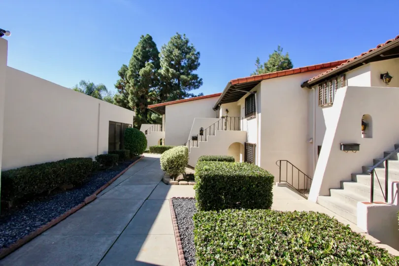 Multiple housing units in white with red roof, stairs leading up to doors and down to doors