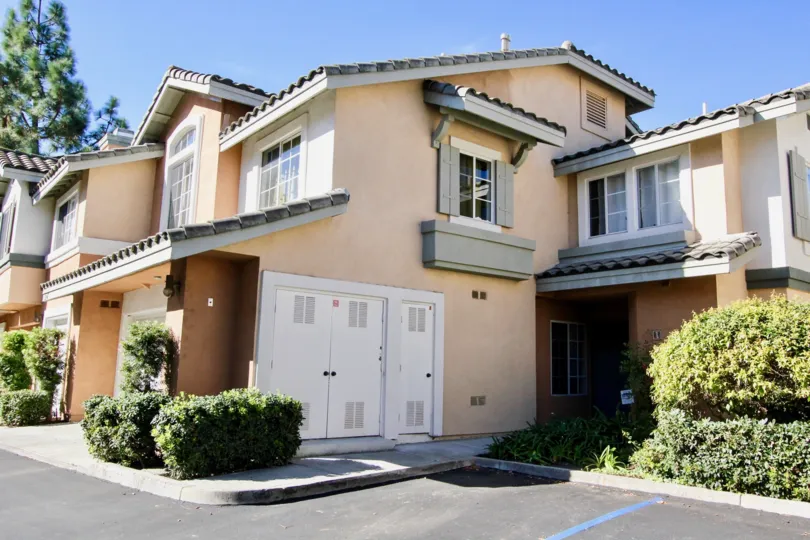 Two story residential units with plants and trees near parking lot at Collage in Rancho Bernardo CA