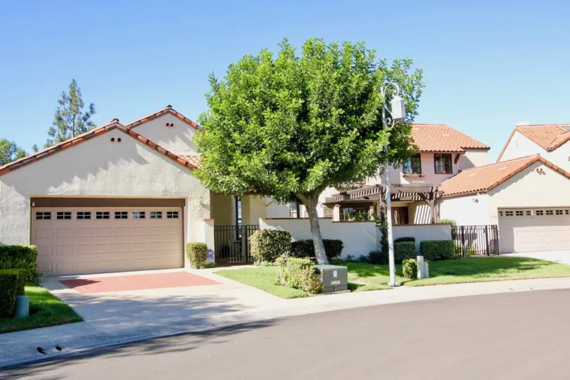 A sunny day in Eastview has villas with trees for shadow in front of the home