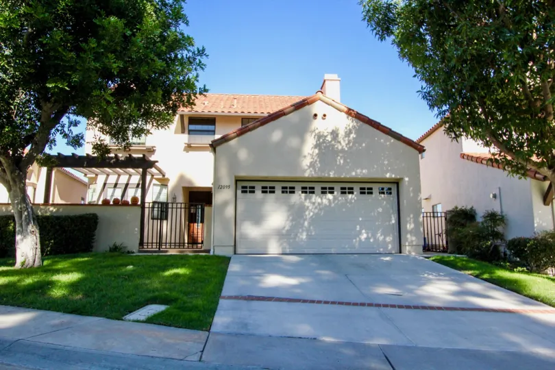 Sunny housing front with green grass and big trees