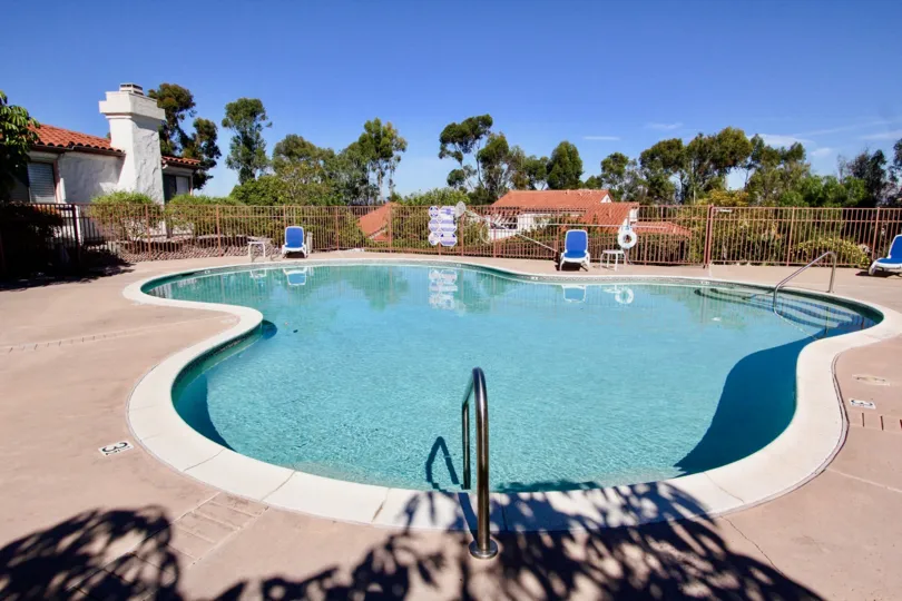 Odd shaped swimming pool with brown security fence at Fairway Vistas in Rancho Bernardo CA