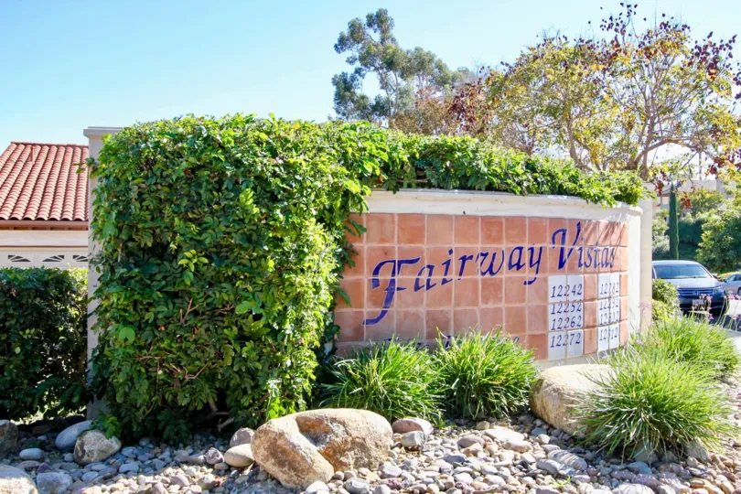 On a pleasant day, Fairway Vistas with several numbers, decorating bushes and trees with car parking
