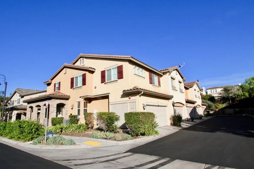 A peach color house with some bushes in front at a corner in Garretson in Del Sur, Rancho Bernardo, CA