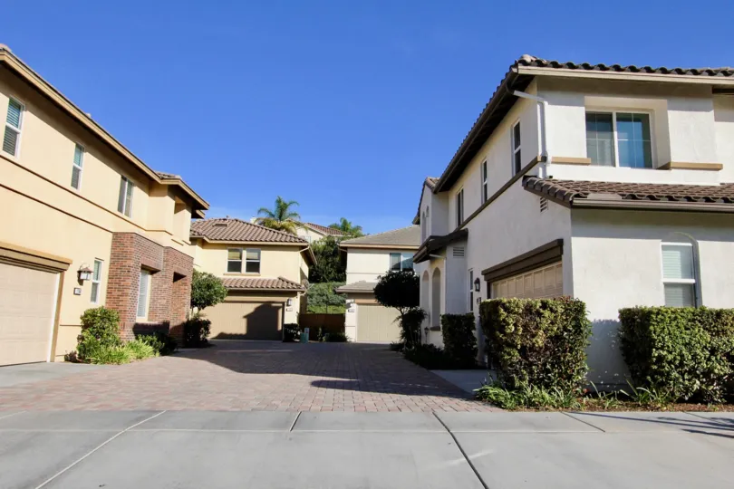 A shared driveway in between houses with some bushes and a sidewalk at Garretson in Del Sur, Rancho Bernardo, CA