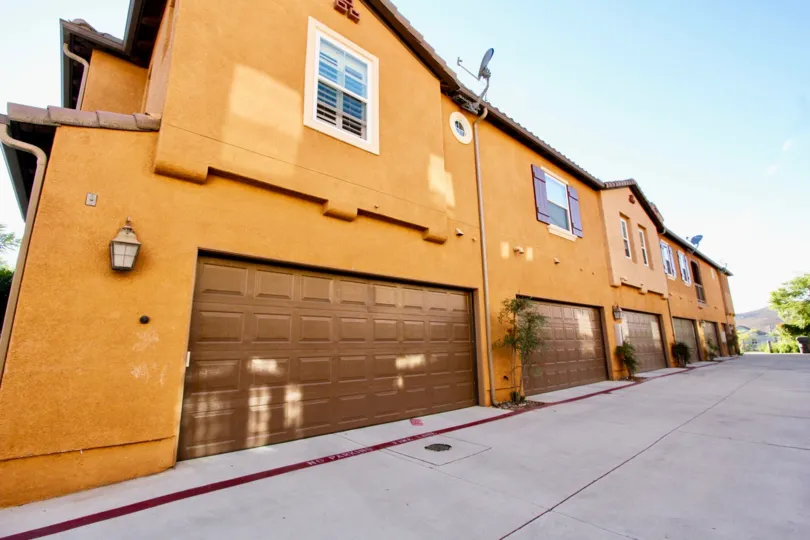 Brown buildings with garages and drive way in Gianni