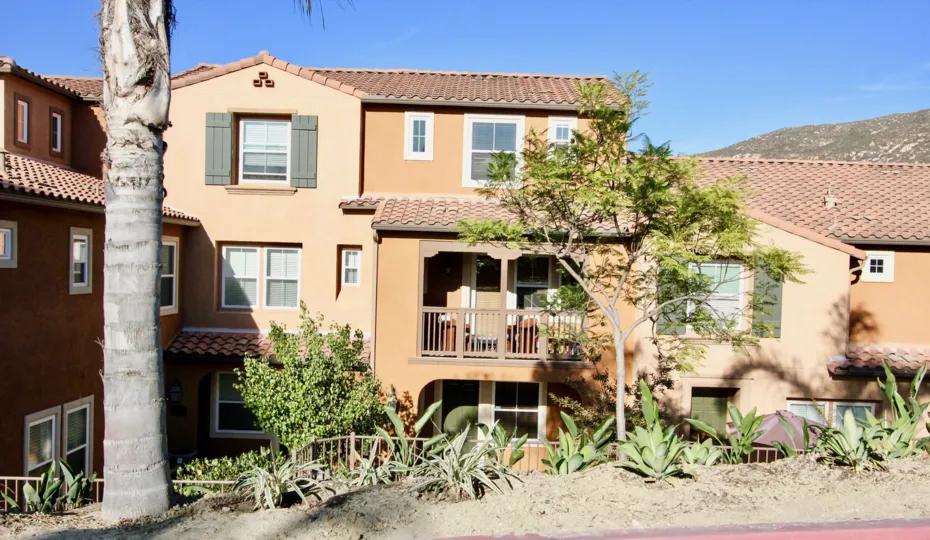 A three story house with porch in Gianni with landscaping