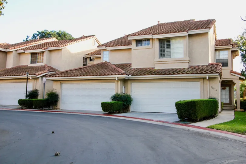 On a sunny day, A street in La Cresta has villas with number 12336 and bushes