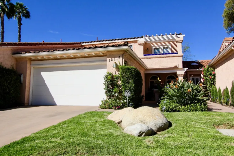 A middle class, beige colored apartment complex, with greenery on a peaceful, sunny day in California.