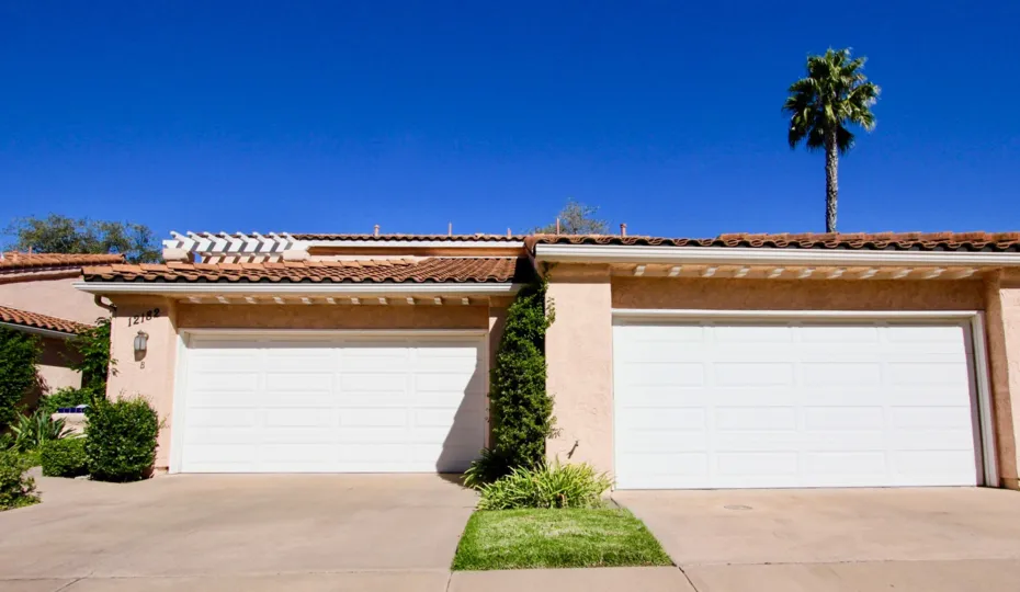 View of a double garage in the community of Masters Hill with green bushes and grass in Rancho Bernardo.