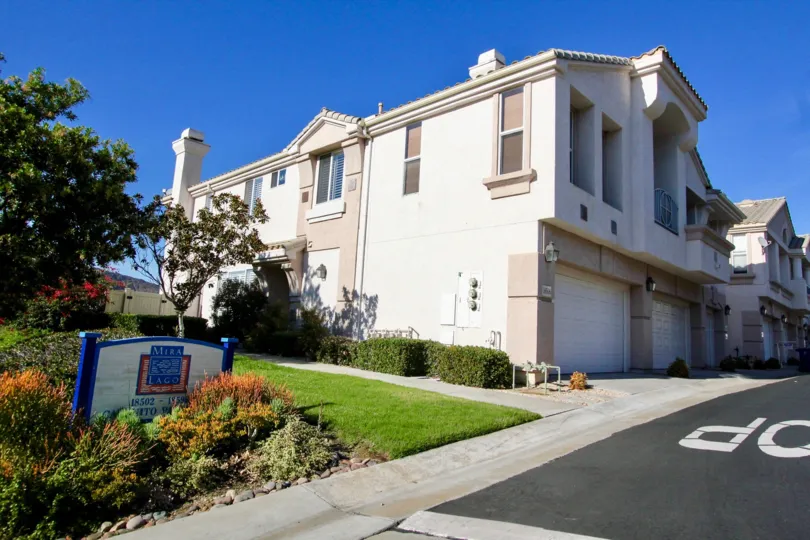 Two story residential building near yard and blue sign at Mira Lago in Rancho Bernardo CA