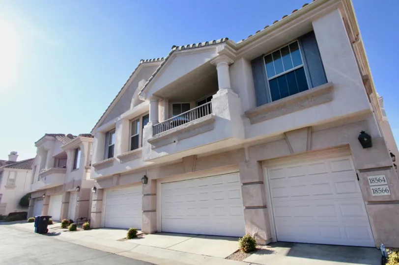 A gray and white big house with a driveway during a sunny day in Mira Lago, Rancho Bernardo, CA