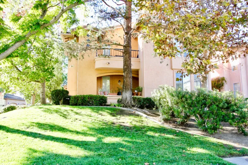 Orange condo building with lots of trees and grass inside Morada in Rancho Bernardo CA