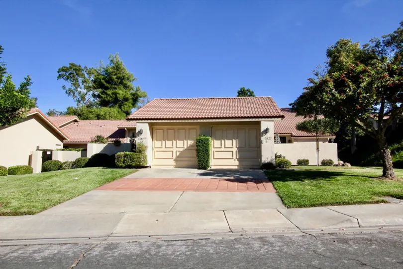 In front view of the apartment in Oaks North Villas has bushes in two sides of the gate