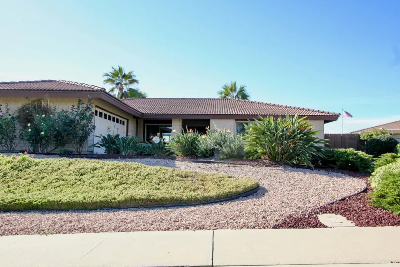 In front of villa in Oaks North has grass, bushes along the path