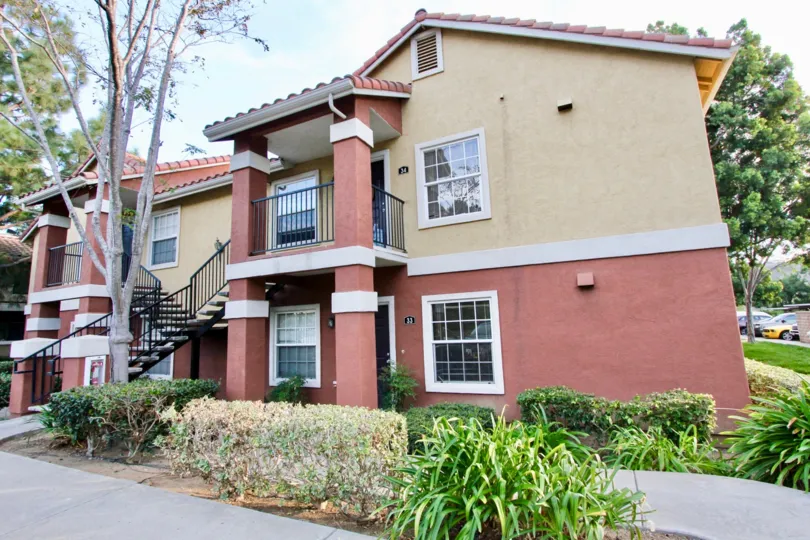 A pink and yellow house with some bushes and trees during a sunny day in Sabre Terrace, Rancho Bernardo, CA